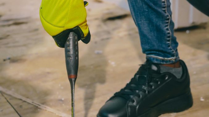 Technische dienst medewerker draagt veiligheidsschoenen tijdens onderhoudswerkzaamheden in een industriële omgeving.